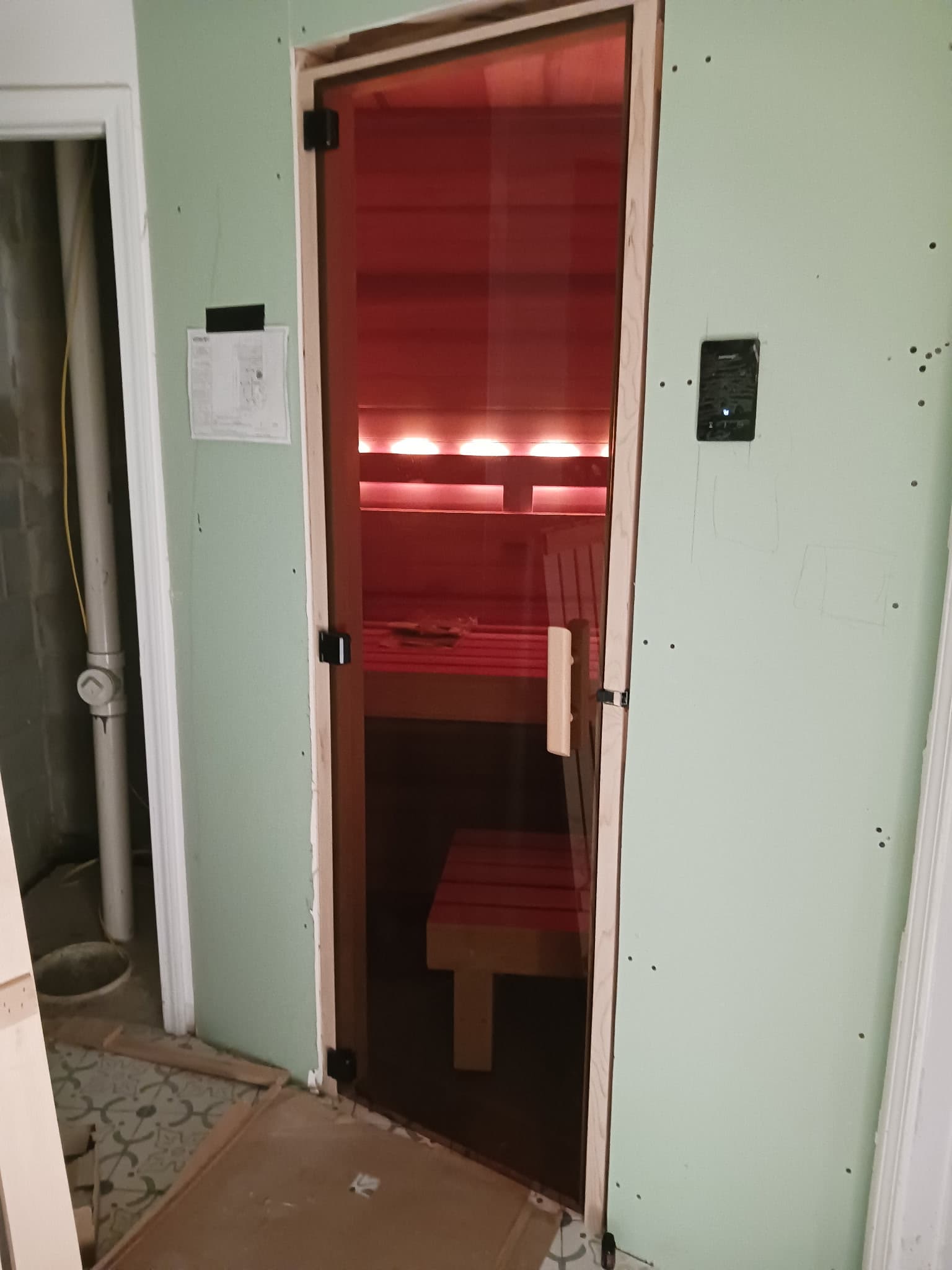 Glass sauna door with red-lit interior visible from the entry.