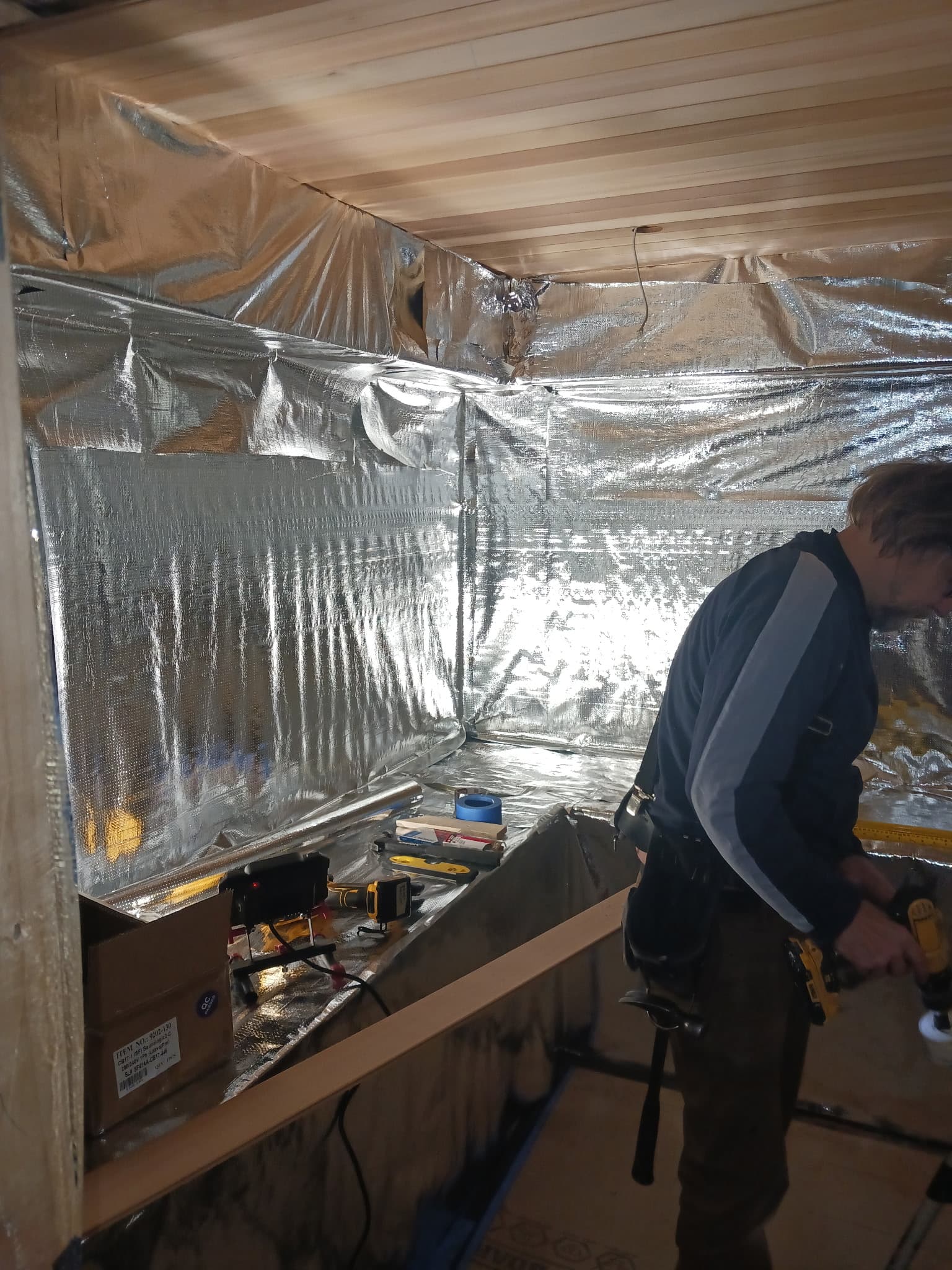 Insulated sauna room preparation with reflective vapor barrier and trades on site.