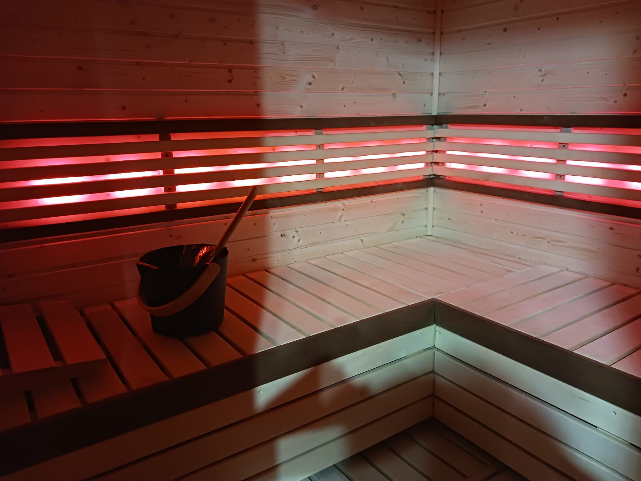Red-lit custom indoor sauna with wraparound benches.