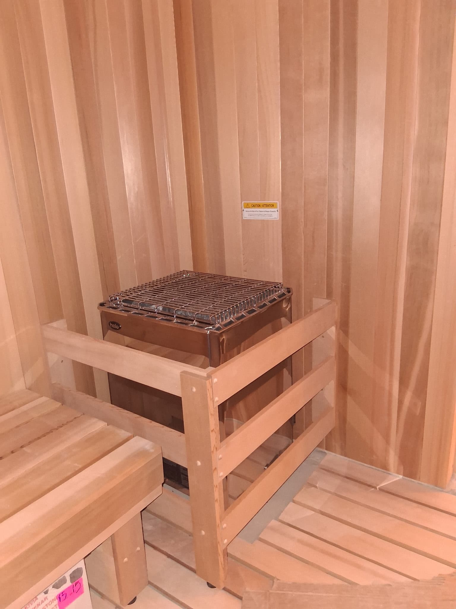 Compact sauna interior with heater and vertical wood walls.