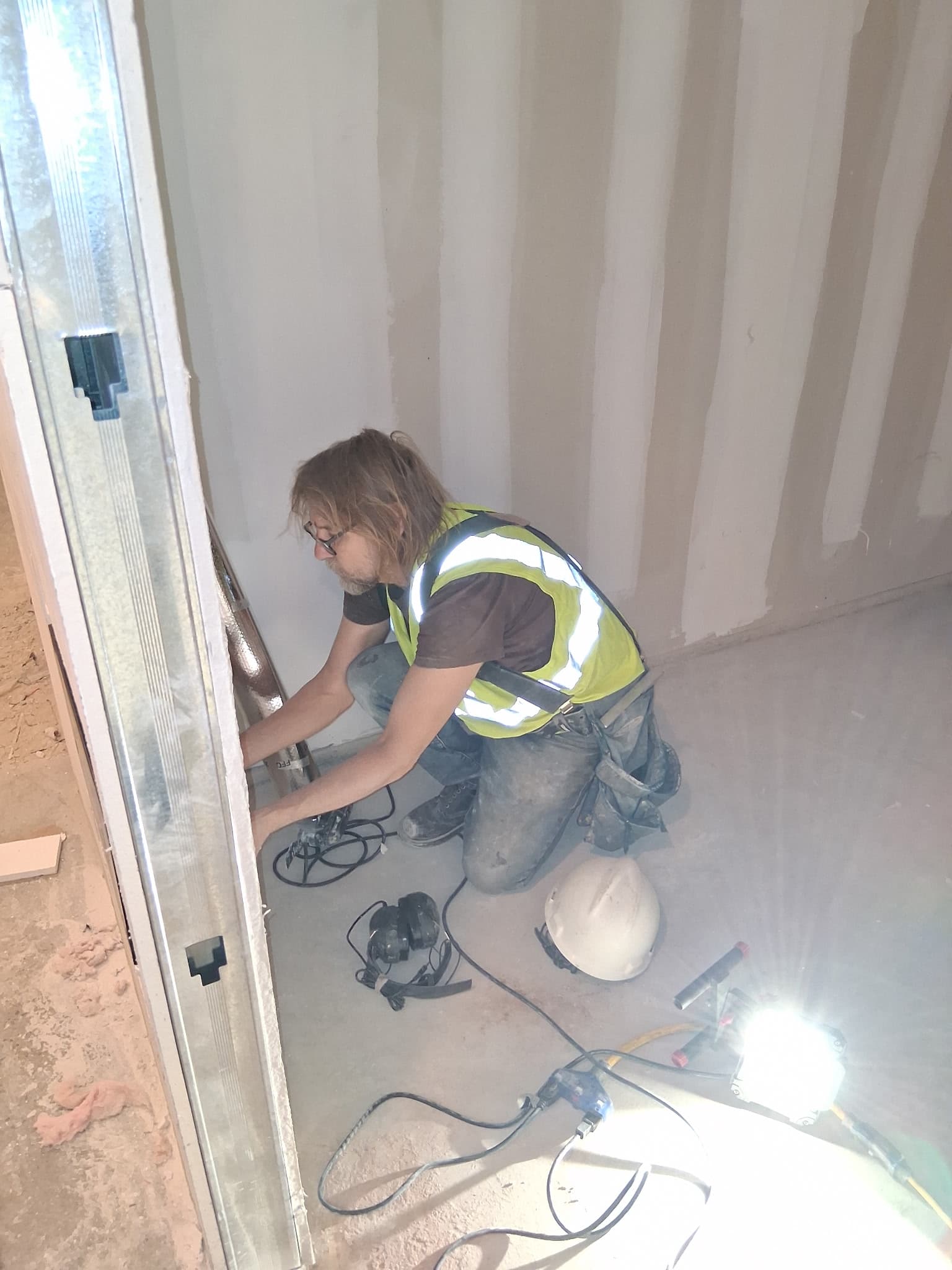 Worker installing hardware at a sauna doorway.