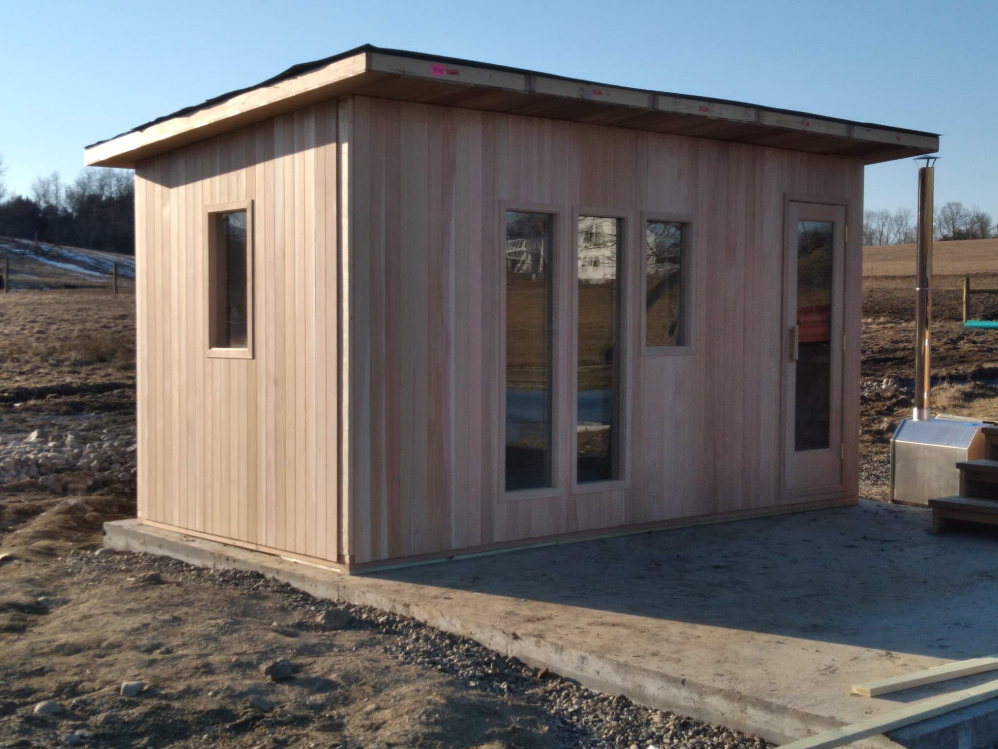 Outdoor sauna building on a prepared site with open field context.