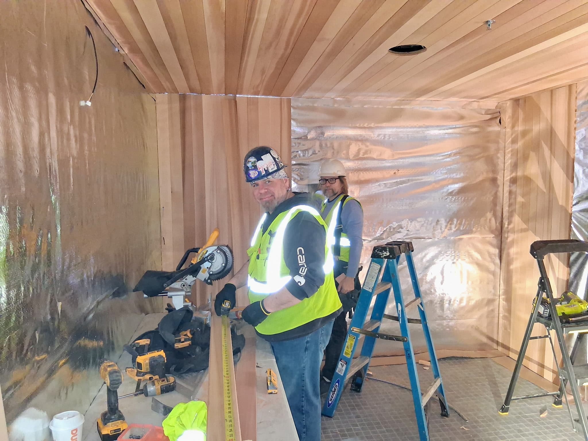 Installers working on a commercial cedar sauna installation.