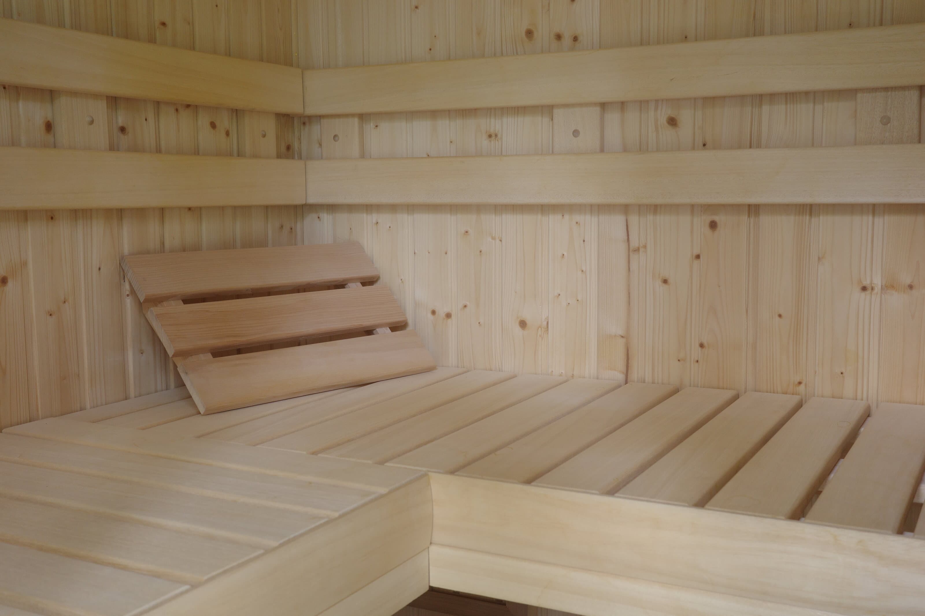 Finished pale wood indoor sauna with clean benches and horizontal backrests.